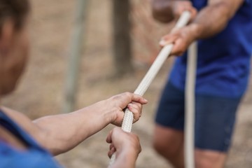 Man and woman playing tug of war during obstacle course