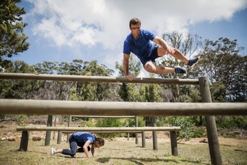 Man and woman jumping over the hurdles during obstacle course