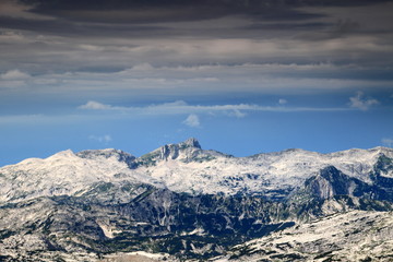 Fototapeta na wymiar Peak of Krn, Julian Alps, Triglav National Park, Slovenia with rocky terrain of limestone slopes and layer of clouds before the storm strikes, seen from Hribarice below Kanjavec
