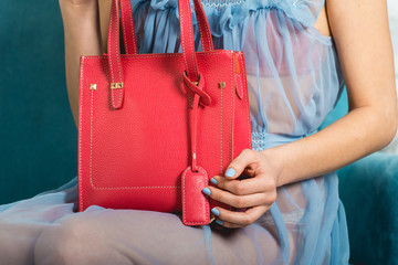 sexy girl in a blue nightgown holds red handbag