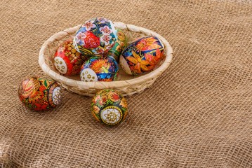 Easter eggs with bright lacquer paintings in a wicker basket on the tablecloth of burlap