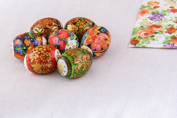 Easter eggs with bright painting on a light background of natural tablecloths and coloured paper serviettes