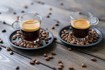 Two cups of espresso and coffee beans on a wooden table