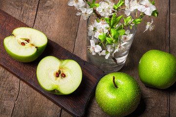 Green apples with blossoms on wooden table