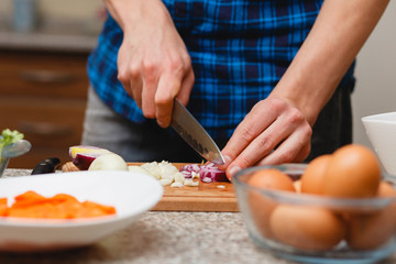 cooking, food and home concept - close up of male hand cutting