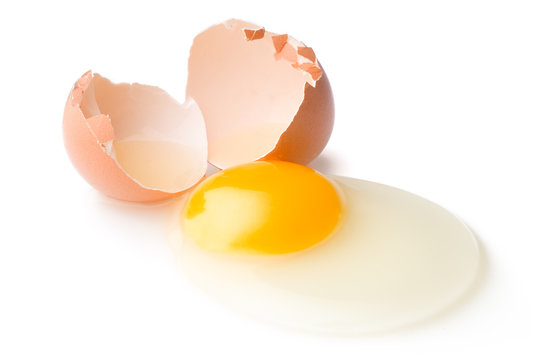A broken chicken egg lies on a white background with a shell, yolk and spilled protein, isolated
