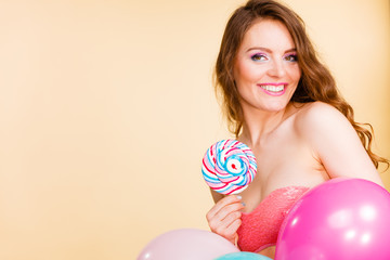 Woman holds lollipop candy and balloons