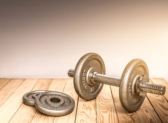 Obraz na płótnie Canvas Dumbbells , weight plates on wooden background for bodybuilder. Concept for sport player or workout. gym of accessories for fitness