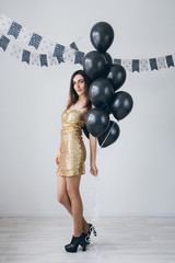 Girl in a gold dress with black balloons