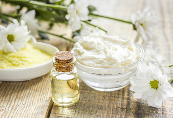 homemade cosmetics with camomile herbs on wooden background