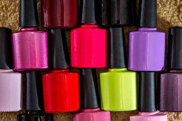 Group of bright nail polishes on wooden desk.