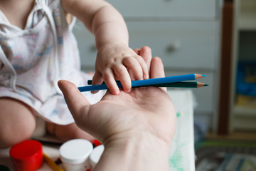 Dad passes color pencils to his child.