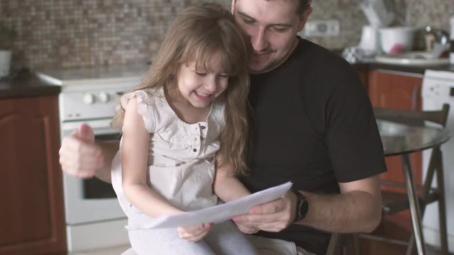 small daughter resorts to dad to show her drawings. Father spends time with his daughter