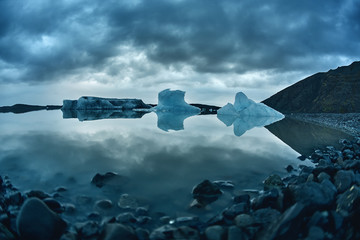 Glacial lagoon in Iceland in the fall. Cloudy foggy weather, mountains on the horizon. The glacial lake reflects the sky, glacier and mountains © vitaliymateha