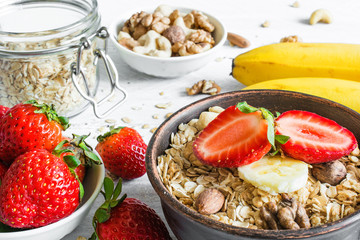 bowl of oat muesli with strawberry, banana, granola and nuts