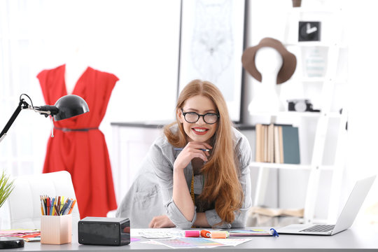 Beautiful young fashion designer working in office