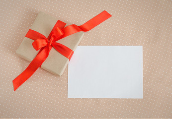 Holiday Post Card Beige Gift Box with Red Ribbon Sheet of Paper Textile Background 
