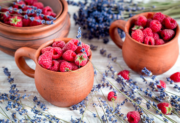 raspberry in pottery and lavender flowers on rustic background