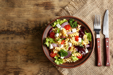 Cold delicious pasta salad on wooden table