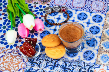 Cup of Arabian Coffee on an Oriental Colorful Background / Cup of Espresso on an Oriental Colorful Background with Flowers, Rings, and Tamr dates 