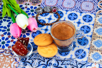 Cup of Arabian Coffee on an Oriental Colorful Background / Cup of Espresso on an Oriental Colorful Background with Flowers, Rings, and Tamr dates 