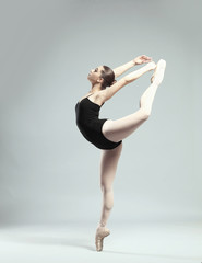 Naklejka premium Young beautiful ballerina dancing on light background