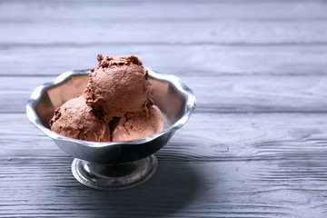 Tasty ice-cream in bowl on wooden table