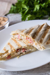 shawarma in thin pita bread with chicken and vegetables on a plate