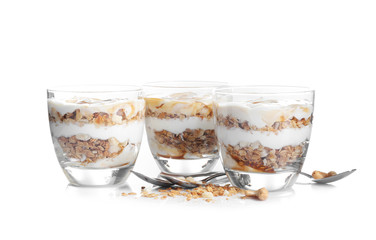 Tasty dessert with yogurt and granola in glasses on white background