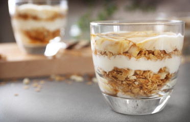 Glass with tasty yogurt dessert on table