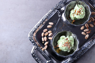 Dessert bowls with delicious pistachio ice cream on metal tray