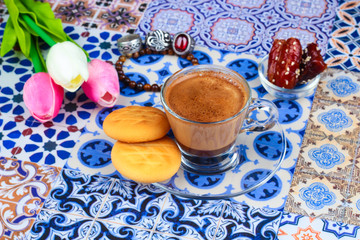 Cup of Arabian Coffee on an Oriental Colorful Background / Cup of Espresso on an Oriental Colorful Background with Flowers, Rings, and Tamr dates 