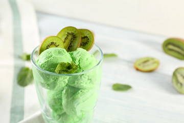 Glass with tasty fruit ice cream on table