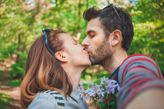 Young couple in love taking a selfie while kissing in the park