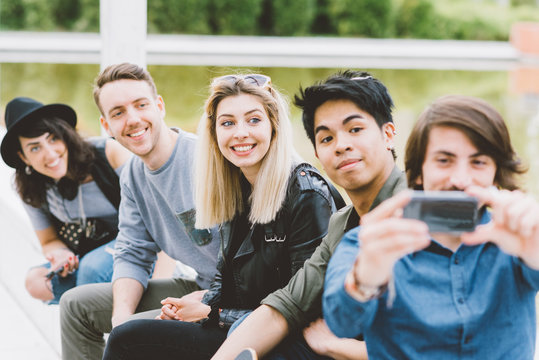 Group of friends multiethnic millennials using smart phone taking selfie - technology, social network, togetherness concept