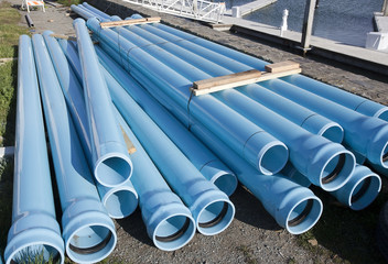 Stacked blue pipes at construction site.