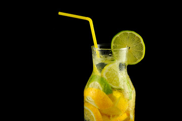 Decanter with soda water, lemons and a straw on a black background.