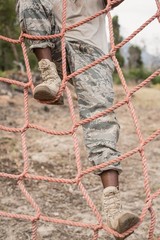 Military soldier climbing a net during obstacle course