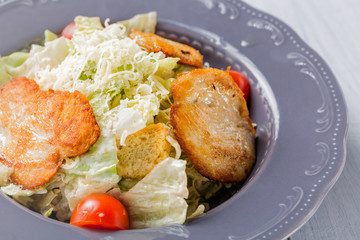 Healthy caesar salad with cheese, chicken and tomatoes in iron plate close up