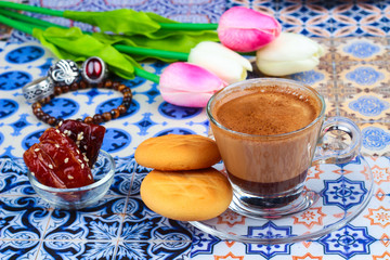 Cup of Arabian Coffee on an Oriental Colorful Background / Cup of Espresso on an Oriental Colorful Background with Flowers, Rings, and Tamr dates 
