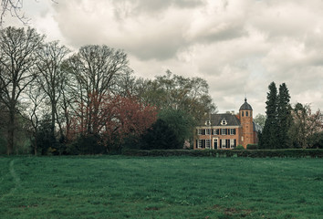 Obraz premium Dutch rural landscape with huge country house under cloudy sky.