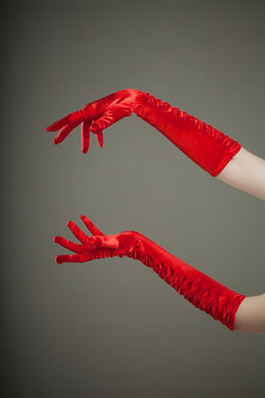 Elegant empty open female hands in red silk or satin gloves, free space presenting your product or text