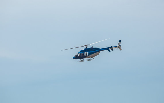 A large, blue helicopter is flying against the blue sky.