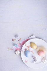 Easter holiday pastel decorations. Colorful eggs, sweet dessert, bunny ears. Top view, copy space.