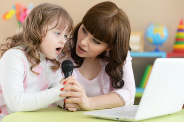Mother and daughter singing at table