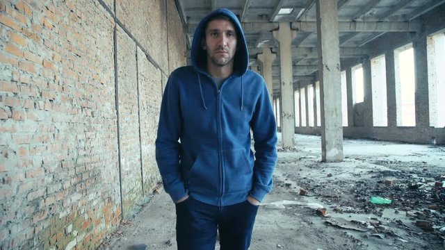 Lonely sad junkie in hood walks in catacombs and looks at camera in 4K