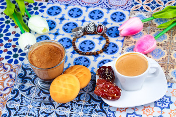 Cup of Arabian Coffee on an Oriental Colorful Background / Cup of Espresso on an Oriental Colorful Background with Flowers, Rings, and Tamr dates 