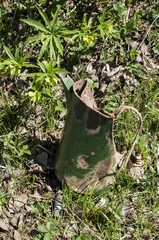 Old battered crumpled grunge green metal jug closeupvon village yard grass meadow
