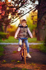 cute kid riding a bicycle through the spring park