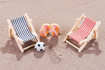 Two empty sun loungers with ball and shoes on the beach